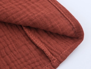 Macro shot of rust orange double cotton gauze fabric texture and fine stitching detail