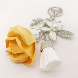 Detail of yellow fabric rose keychain with white tassel and rhinestone flower charm