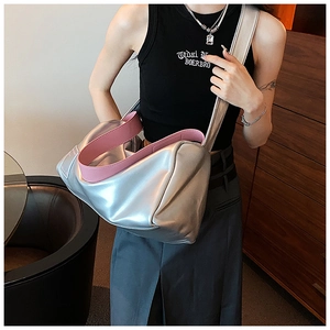 Detailansicht der silbernen Metallic-Zylindertasche mit rosa Griff am Modemodell
