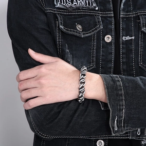 Close-up of thick silver Cuban link bracelet on male model wearing a denim jacket