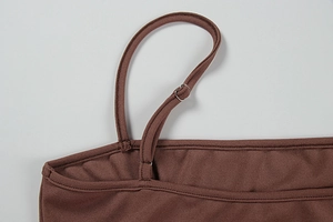 Détail des bretelles réglables et de la boucle en métal sur une robe en maille marron