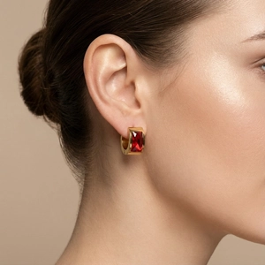 Macro detail of a gold titanium steel earring with a large rectangular red zircon stone