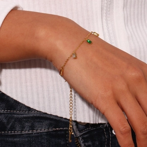 Detailed shot of a minimalist gold bracelet with square colored zircon gems on a wrist