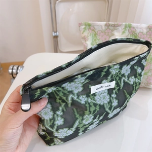 Close-up of mesh makeup bag showing white floral embroidery and spacious interior compartment
