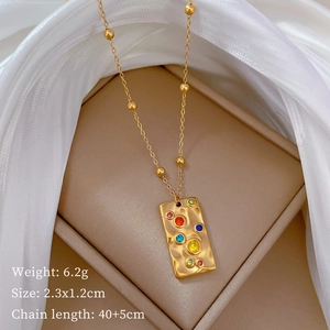 Macro shot of gold square textured pendant with small colorful gems in a gift box