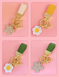 Detail of four colorful PU leather flower keychains with golden hardware on pink background