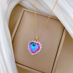 Close-up of golden heart pendant with purple-blue crystal in a luxury jewelry box