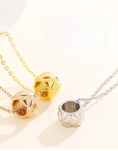 Macro detail of cylinder pendants with quilted diamond pattern in gold, rose gold and silver