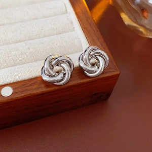 Detailed view of silver knot stud earrings on a velvet display box with metallic luster