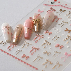 3D bow nail art stickers with gold foil accents and floral patterns on elegant press-on nails