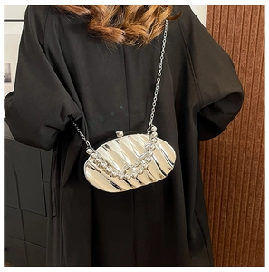 Detail of silver shell-shaped acrylic clutch bag with pearl handle and metal chain strap