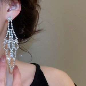 Detailed view of silver dangle earrings with sparkling rhinestones on a female model