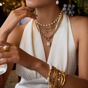 Close-up of layered 18k gold stainless steel pearl necklaces and baroque pendant jewelry