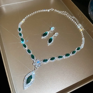 Macro view of silver floral jewelry set featuring marquise emerald stones and diamonds