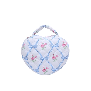 Heart-shaped quilted makeup bag with pink floral patterns and a blue ribbon bow