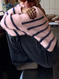 Close-up of pink knit sweater with navy blue stripes in a soft mohair texture