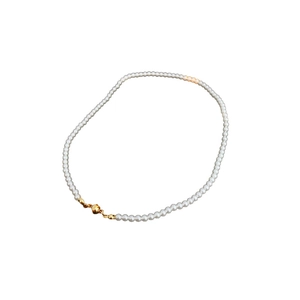Classic white pearl necklace with a minimalist gold magnetic clasp on white background