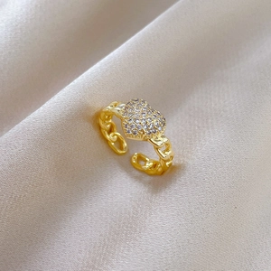Detailed view of gold plated heart ring with pavé zircons on champagne silk cloth