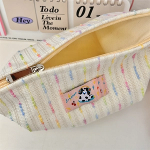 Détail de la trousse de maquillage en tweed tissé avec rayures arc-en-ciel