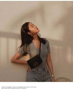 Detail of black leather crossbody bag with CD metal logo and premium sunset lighting