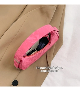 Detailed interior of a pink pleated crescent bag showing storage for phone and makeup