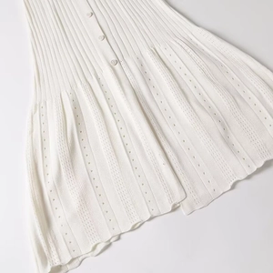 Close-up of white knitted fabric texture with elegant button details on a slim summer dress
