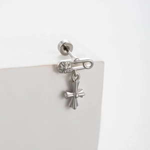 Silver stainless steel safety pin earring with cross pendant on a white pedestal