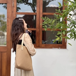 Outdoor view of vintage checkered cotton tote bag with leather straps on model shoulder