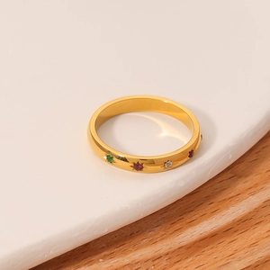 Gold stainless steel ring with colorful zircon stones on a white tray, minimalist jewelry