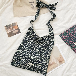 Detail shot of black floral canvas shoulder bag with tie-up bow strap and white logo label