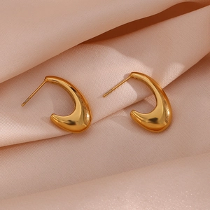 Minimalist gold curved hollow earrings on soft pink pleated silk fabric background