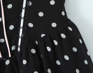 Detail des schwarzen Polka-Dot-Kleides mit Spitzenbesatz und rosa Trägern