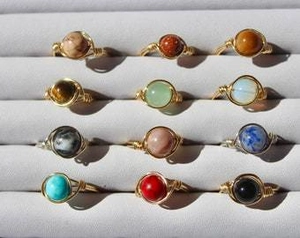 Macro shot of colorful natural stone beads and hand-woven copper wire rings on a tray