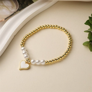 Detail eines Perlenarmbands mit goldenen Metallkugeln, Perlen und einem Herzanhänger