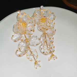 Macro shot of acrylic flower tassel earrings with gold edges and sparkling crystals