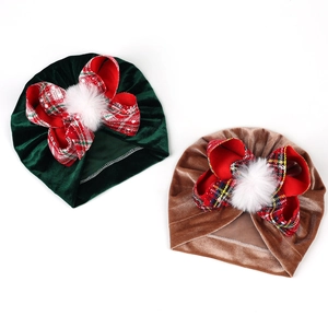 Detail of velvet baby turbans with red plaid bows and white faux fur pom poms