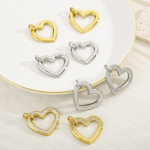 Detailed view of heart-shaped 18K gold and silver pendants on a ceramic tray