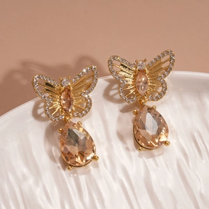 Macro detail of butterfly earrings with champagne crystals and sparkling diamond accents