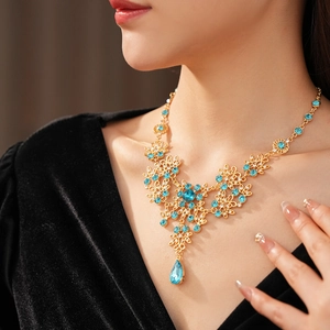 Close-up of vintage flower necklace with blue crystal teardrop pendant on female neck