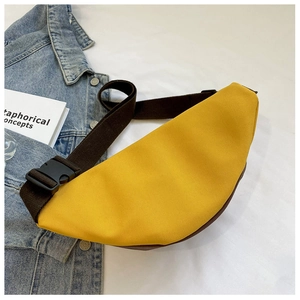 Detailed view of a yellow canvas waist bag with adjustable strap on denim background