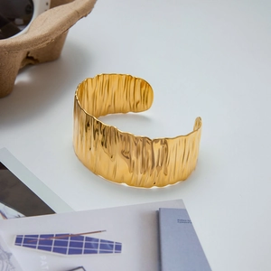 Detailed view of wide gold cuff bracelet featuring unique tree bark texture finish