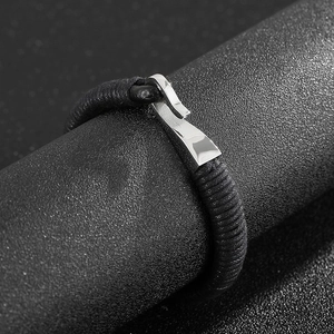 Men's braided leather bracelet with silver stainless steel hook clasp on dark background