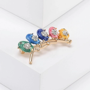 Detail of colorful enamel birds on a branch with sparkling rhinestones and gold plating