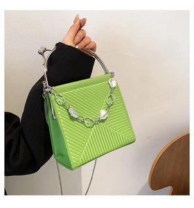 Detail of lime green textured handbag with metallic clasp and decorative chain accent