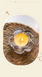 Macro view of plum blossom glass candle holder with burning tealight on dark mat