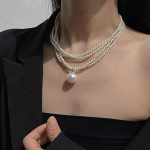 Detail of multi-layer white pearl necklace with single central pendant on model