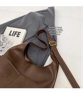 Detail der dunkelbraunen Leder-Eimertasche mit verstellbarem Riemen und goldener Schnalle