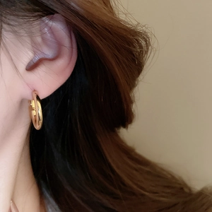 Close-up of polished gold hoop earrings on a model with warm lighting and minimalist style
