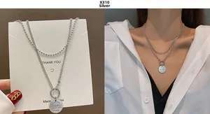 Detail of double layered silver chain necklace with vintage coin pendant on model