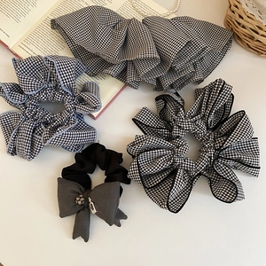 Dettaglio di elastici scrunchie in tessuto vichy con fiocco elegante e ciondoli in metallo